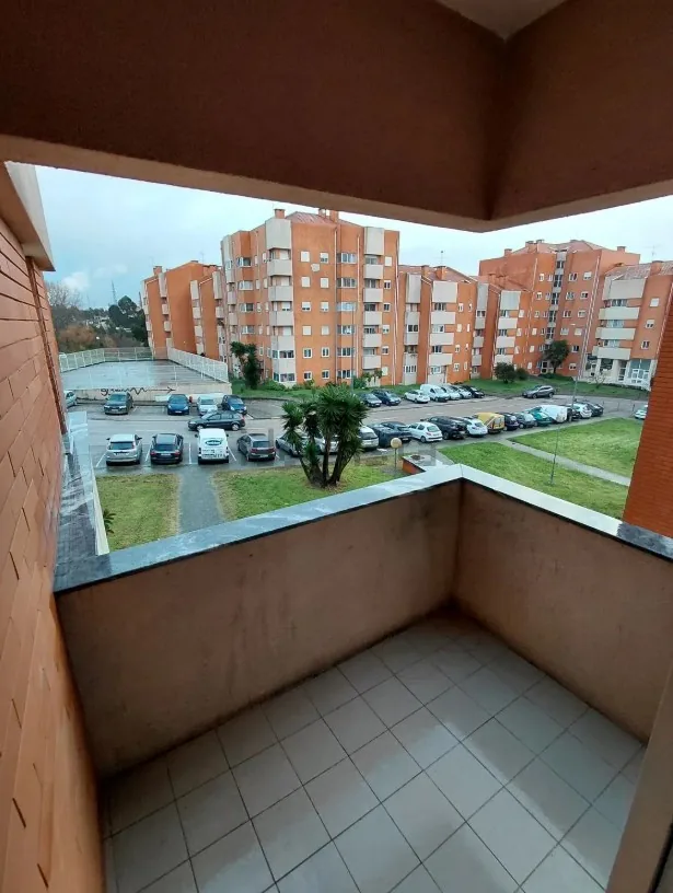 Varanda do apartamento, com vista sobre o estacionamento e os prédios da envolvente