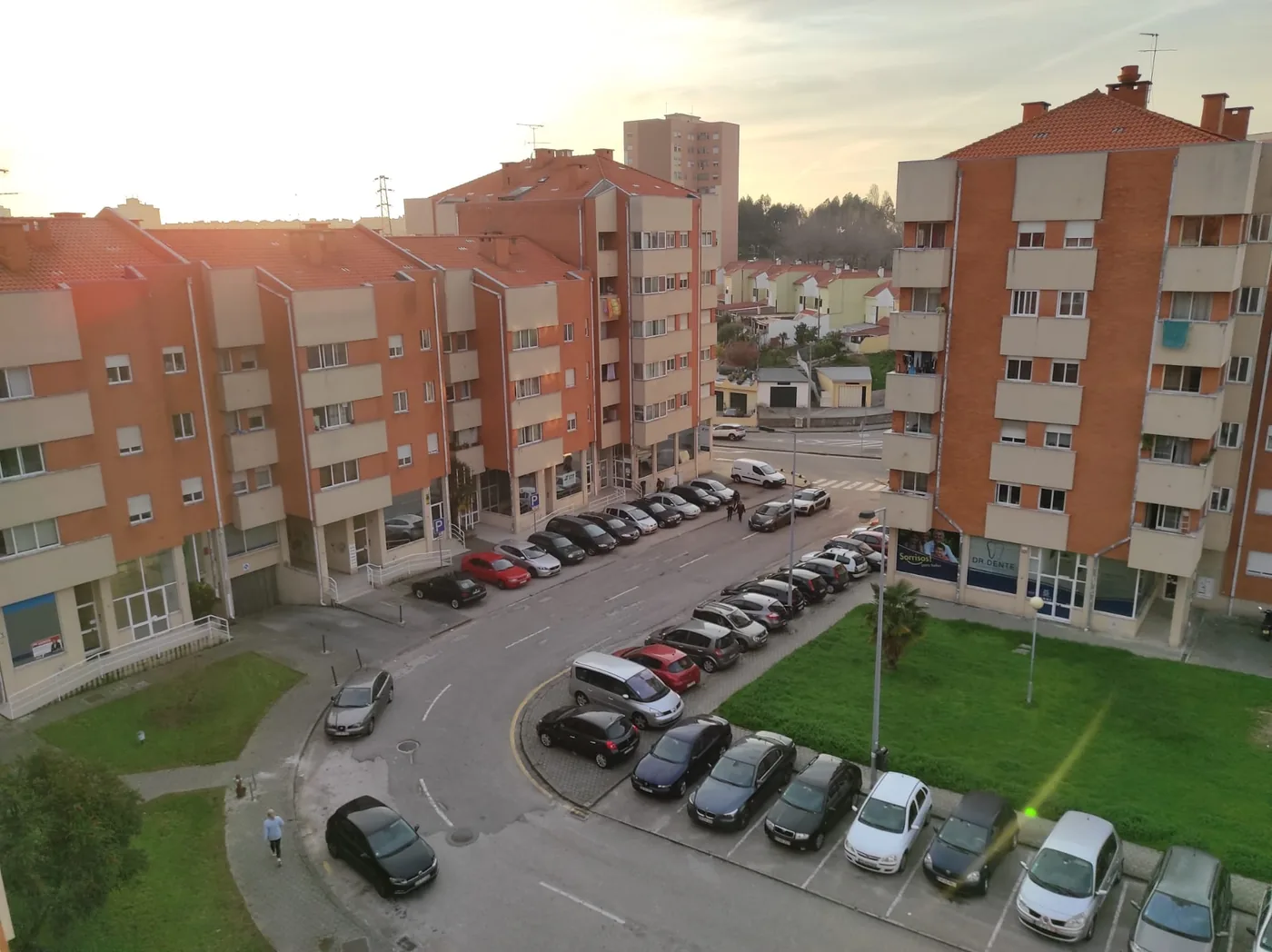 Vista da envolvente do apartamento T3 na Cidadela de Esgueira, com os prédios e o estacionamento do bairro ao fim da tarde