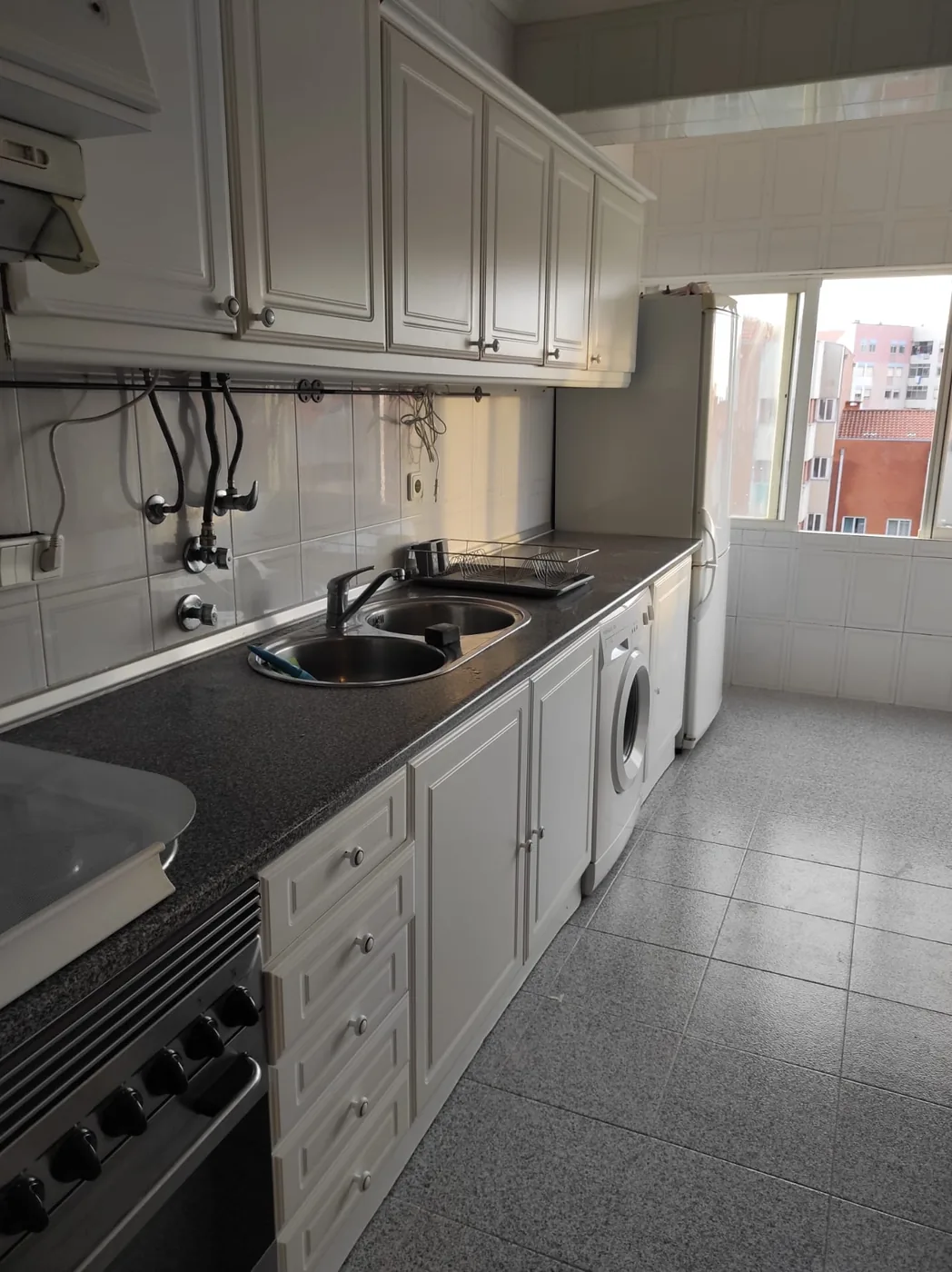 Cozinha do T3 equipada com fogão, forno, exaustor, lava-loiça e máquina de lavar roupa