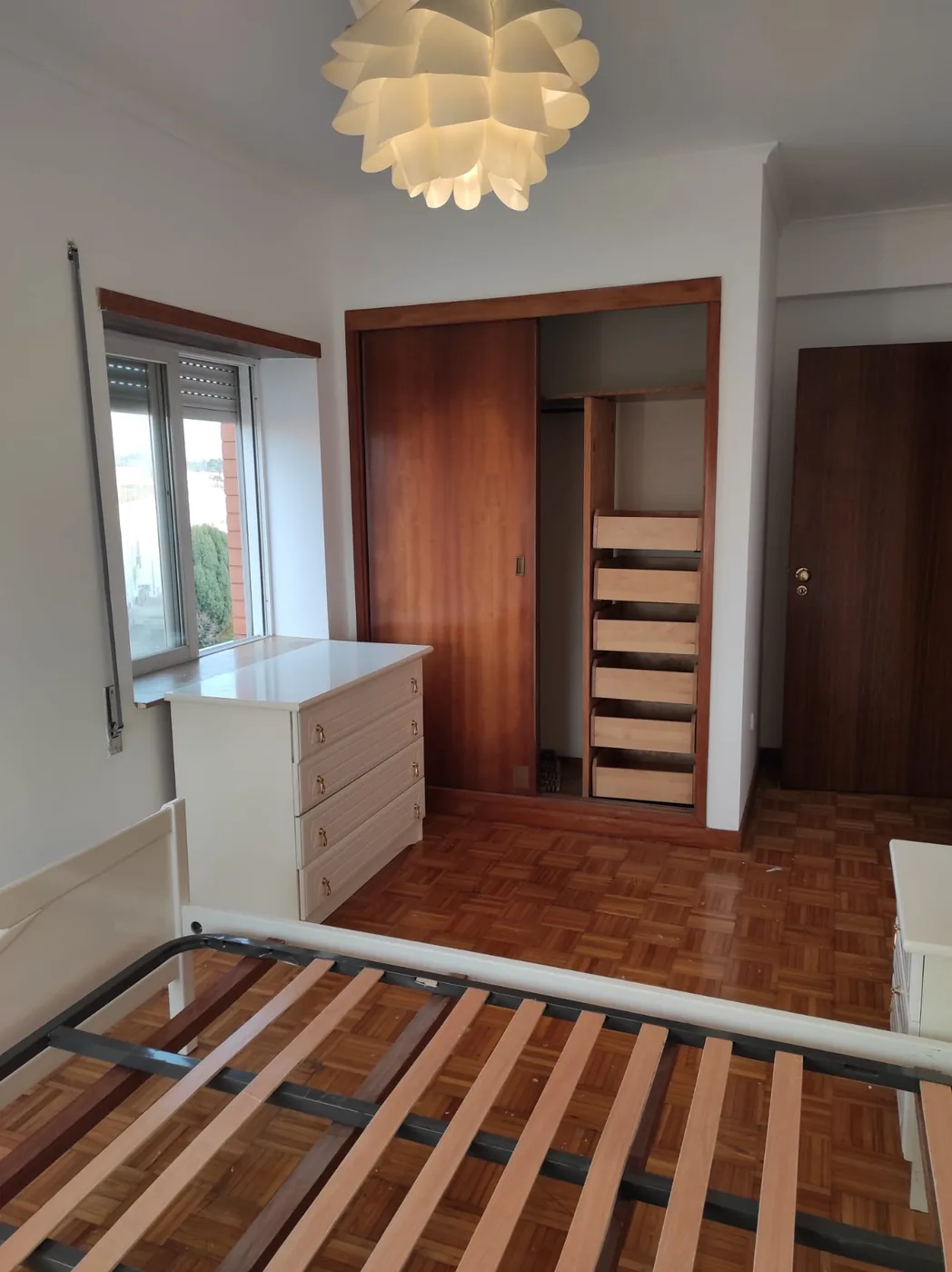 Quarto do T3 com candeeiro de tecto, roupeiro embutido e janela para a rua